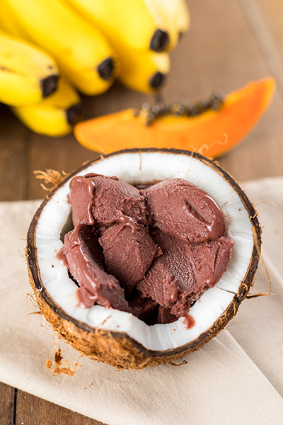 Açaí Na Casca De Coco Com Frutas No Fundo Sobre Uma Mesa De Madeira