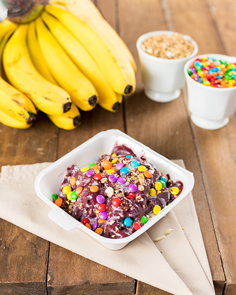 Açaí Na Tigela Com Leite Condensado E Chocolate Sobre Uma Mesa De Madeira