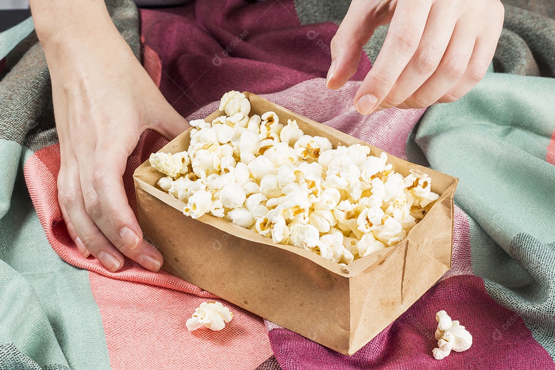 Pipoca No Saco Sobre Tecidos Coloridos E Mãos Segurando o Saco