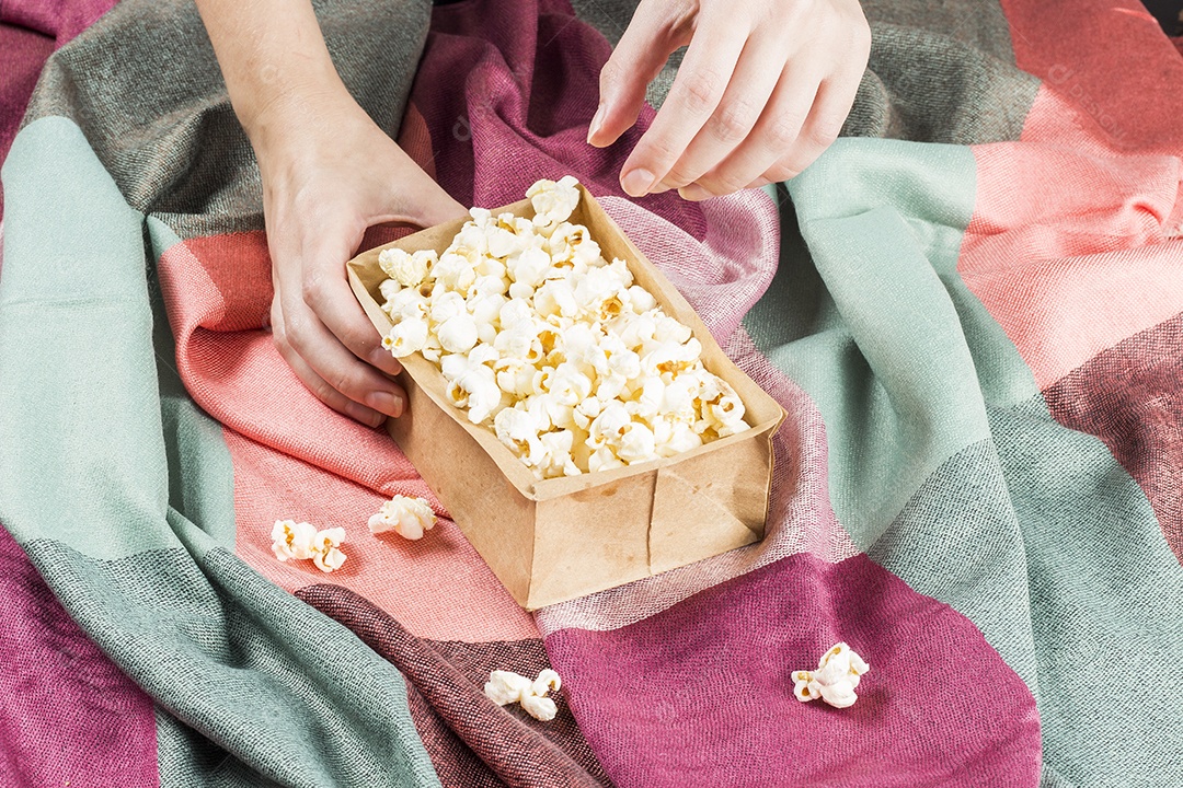 Pipoca No Saco Sobre Tecidos Coloridos E Mãos Segurando o Saco