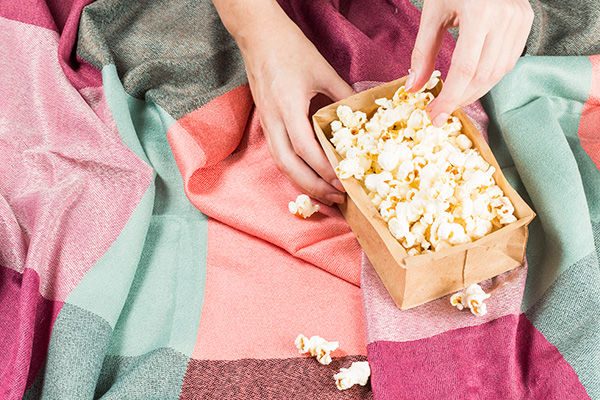 Pipoca No Saco Sobre Tecidos Coloridos E Mãos Segurando o Saco