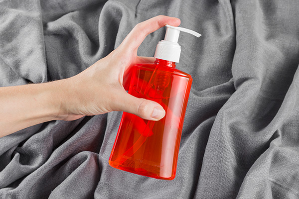 Mão Feminina Aplicando Álcool Em Um Fundo De Tecido Cinza