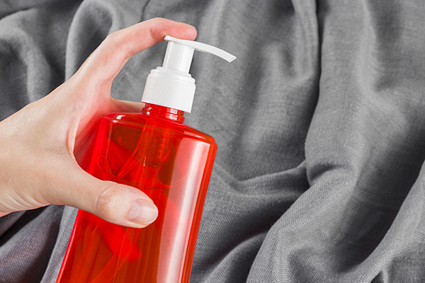 Mão Feminina Aplicando Álcool Em Um Fundo De Tecido Cinza