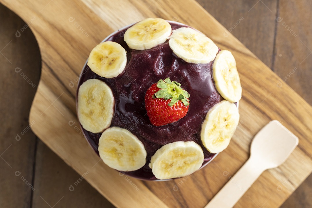 Tigela de Açaí com Bananas e um Morango Sobre Tábua de Madeira Visto de Cima