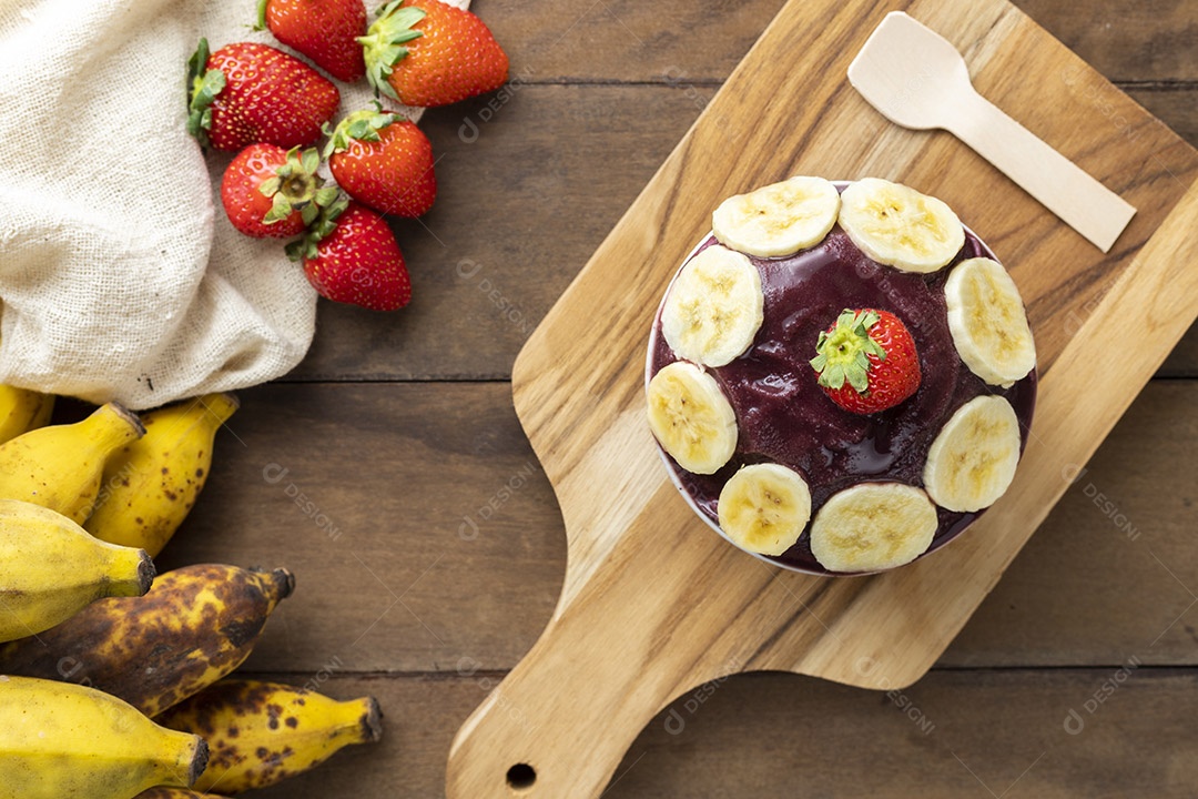 Tigela de Açaí com Bananas e um Morango Sobre Tábua de Madeira Visto de Cima