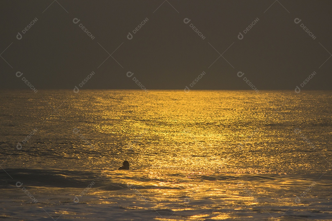 Oceano ao Pôr do Sol com um Banhista