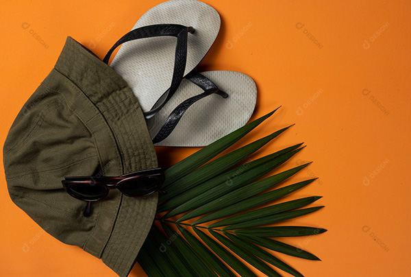 Objetos de Praia e Folhas de um Chapéu em Fundo Laranja