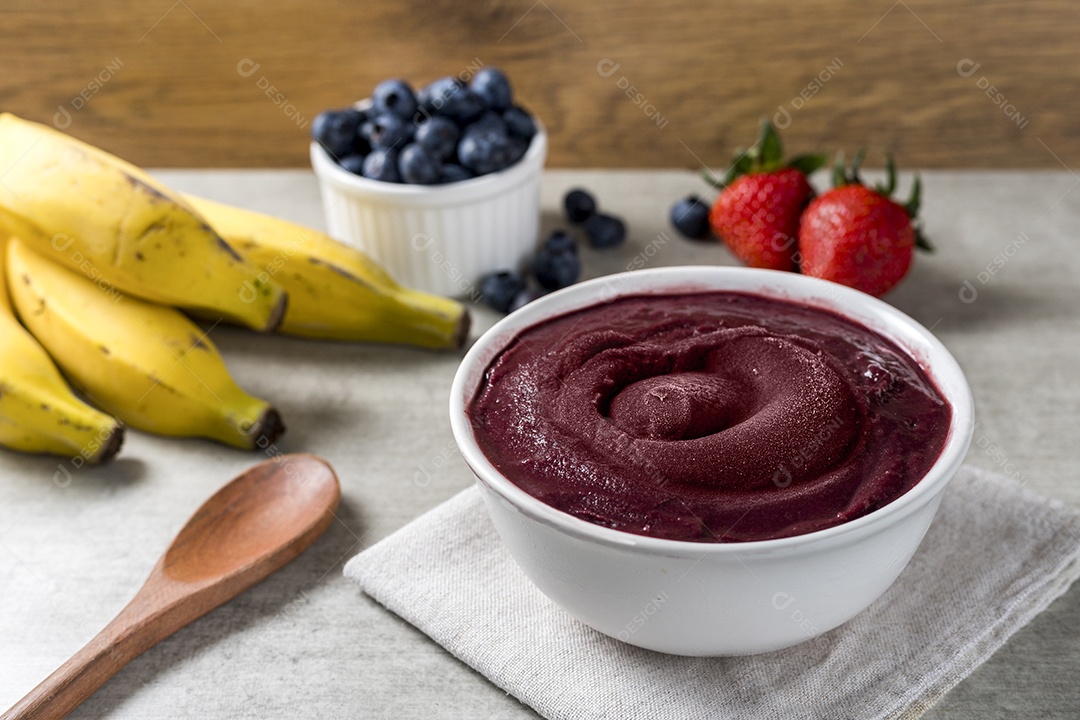 Acai bowl on a wooden table with fruits in the background