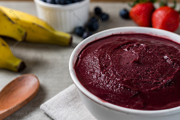 Pote de Açaí Sobre Mesa de Madeira com Frutas no Fundo