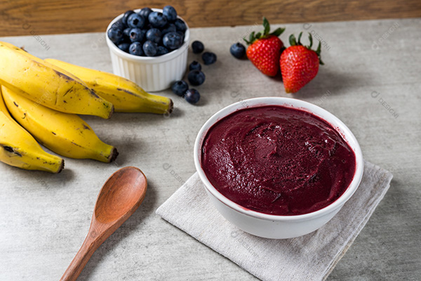 Pote de Açaí Sobre Mesa de Madeira com Frutas no Fundo
