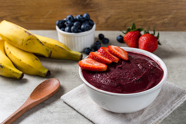 Pote de Açaí com Morangos Sobre Mesa de Madeira com Frutas no Fundo