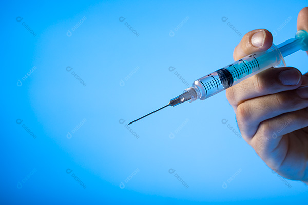 Mão Segurando Seringa Sobre Fundo Azul