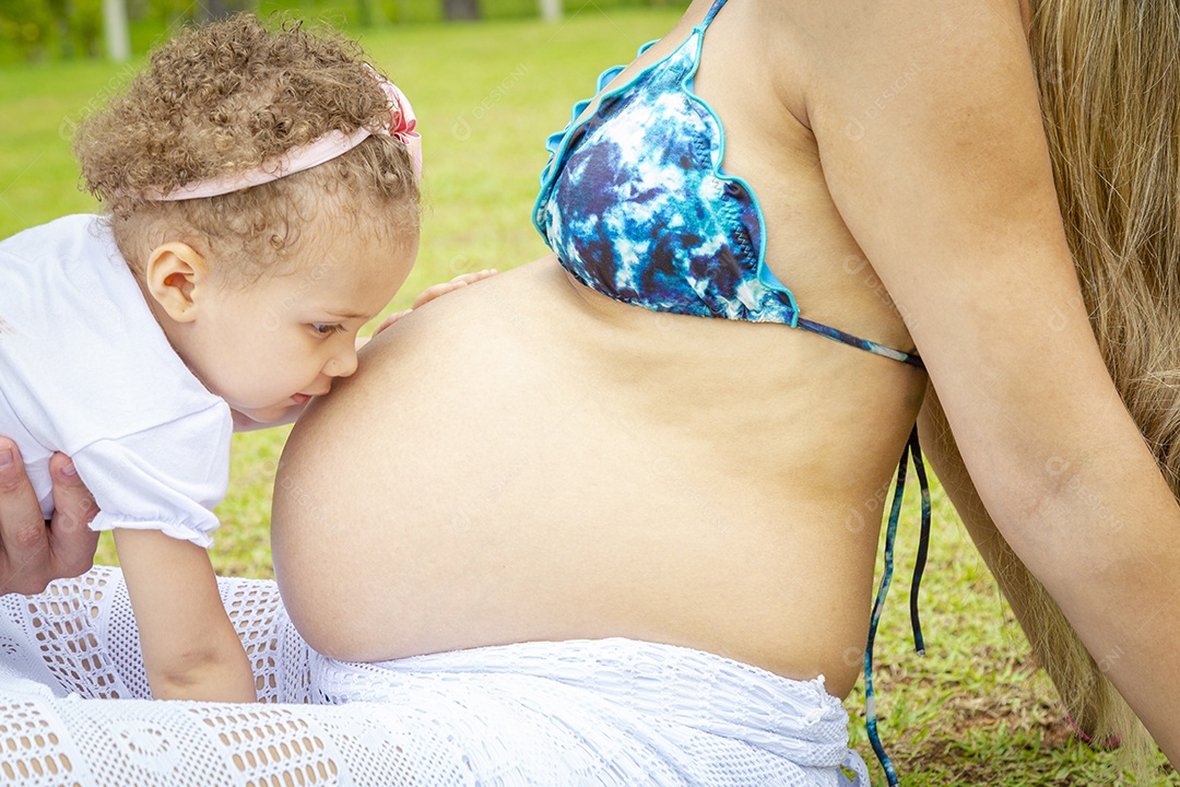 Mulher Grávida Sentada no gramado Com um Bebê Beijando sua Barriga Imagem JPG