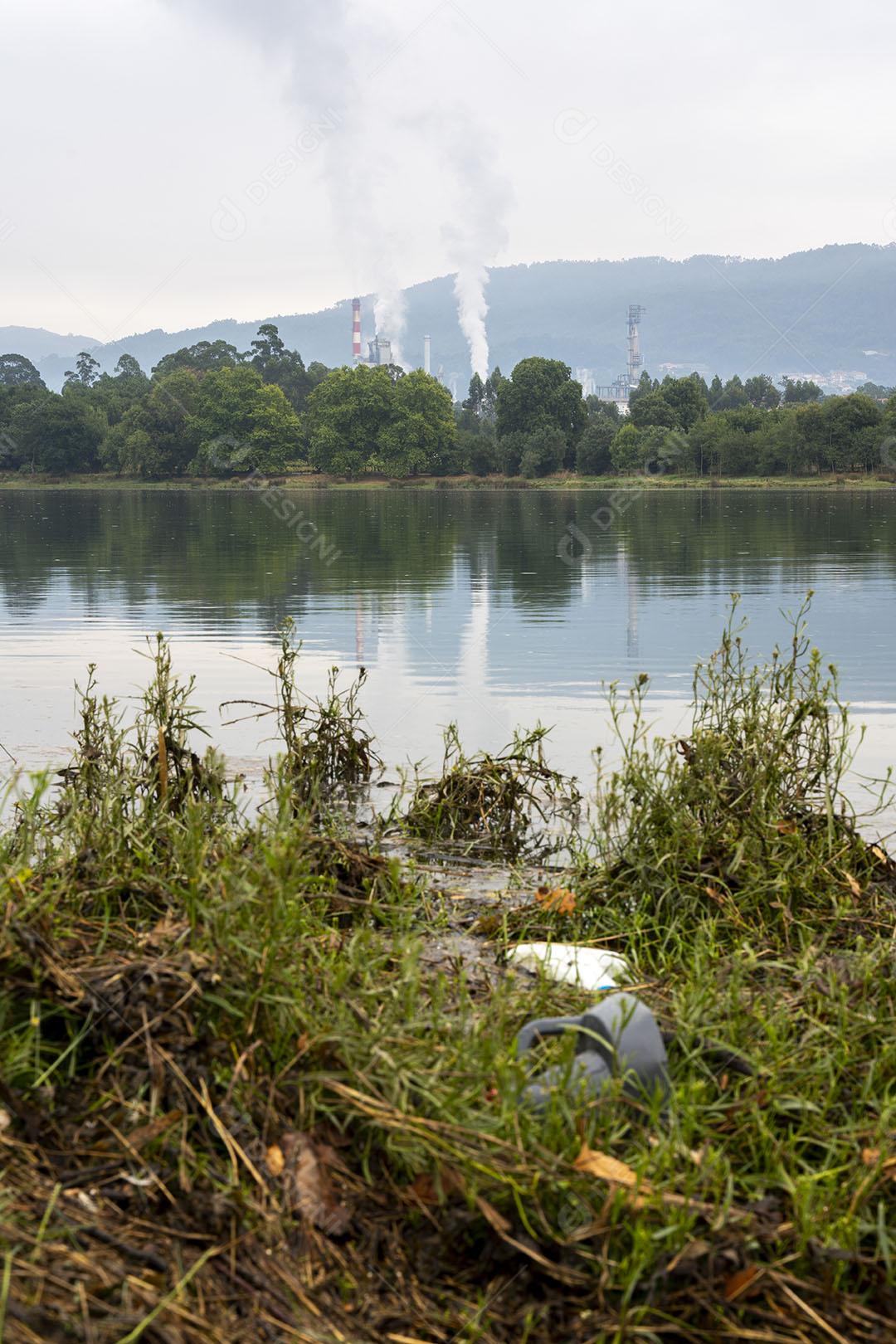 Fábrica Com Usina Exalando Fumaça no Meio da Natureza à Beira do Rio Imagem JPG