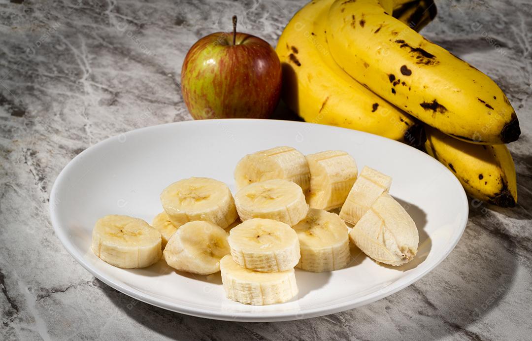 Um Cacho De Bananas  Uma Banana Fatiada E Uma Maçã Em Um Prato Sobre A Mesa Imagem JPG