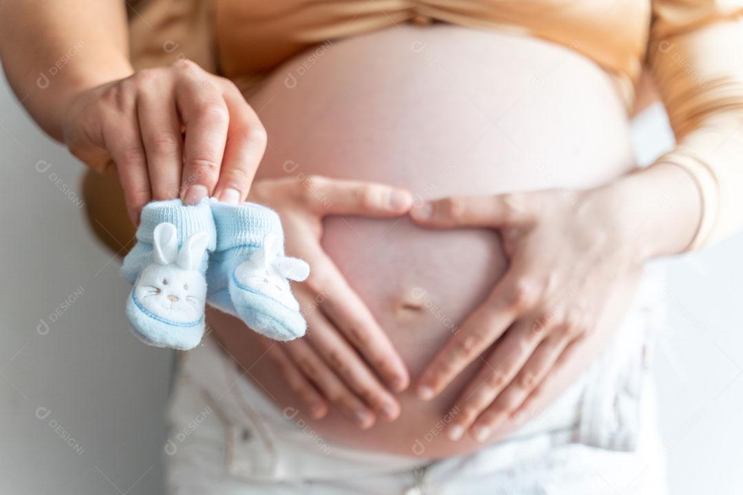 Gravida Com As Mãos Na Barriga E Com Sapato De Bebe Nas Mãos Imagem JPG