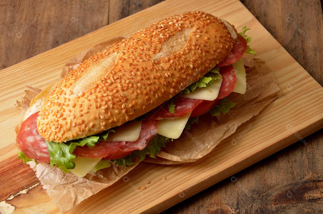 Pão De Baguette Recheada Com Salame Tomate Queijo E Alface Na Tábua Imagem JPG