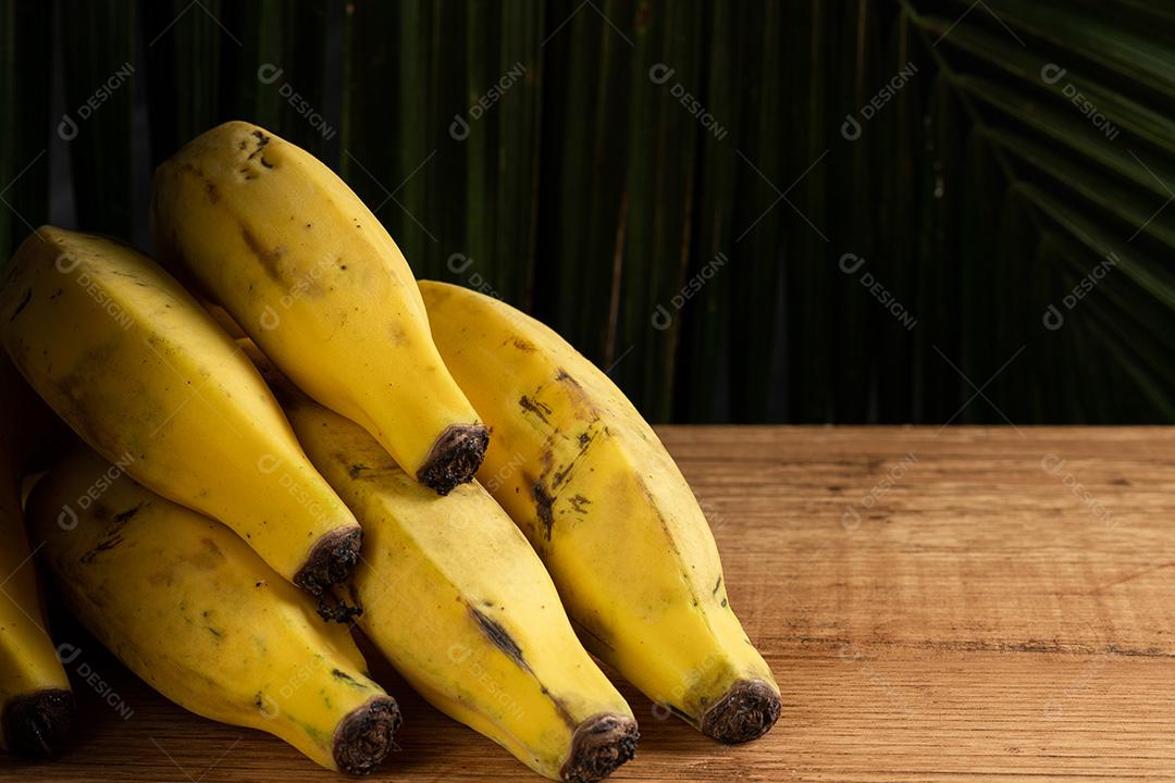 Bananas Na Mesa De Madeira Com Palmeira Folhas Em Fundo Escuro