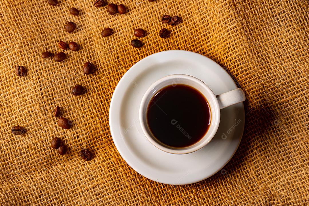 Xícara De Café Branca E Grãos Encima De Pano Sobre A Mesa Imagem JPG