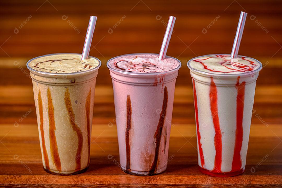 Foto Milk Shake Em Copos Plásticos Canudos Mesa de Madeira Escura Imagem JPG