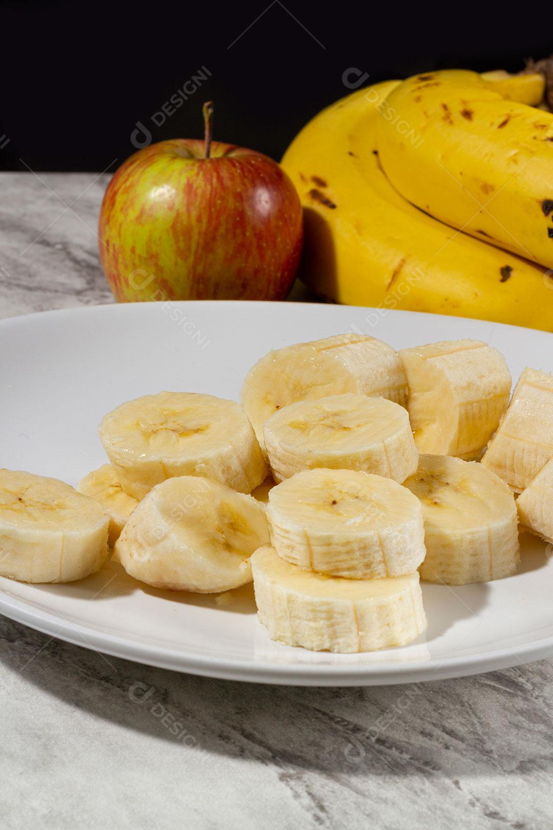 Maçã e Cacho de Banana e Fatias de Banana Em Um Prato Sobre Uma Mesa Imagem JPG