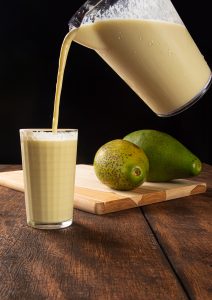 Bebida De Abacate Com Leite No Copo E Abacate Em Uma Tábua Polida Imagem JPG