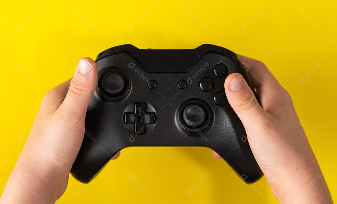 Controlador de Console de Jogos Preto na Mão Em Um Fundo Amarelo Imagem JPG