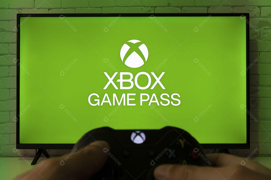 Xbox Game Pass na Tela da Tv Com o Controle Xbox nas Mãos do Homem Imagem JPG