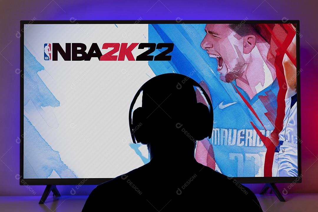 Menino jogando NBA 2K22 na TV com controle do Playstation 5 Imagem JPG