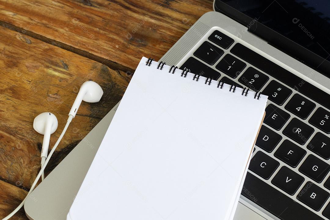 Fotos Bloco de notas em branco sobre um laptop na mesa de madeira