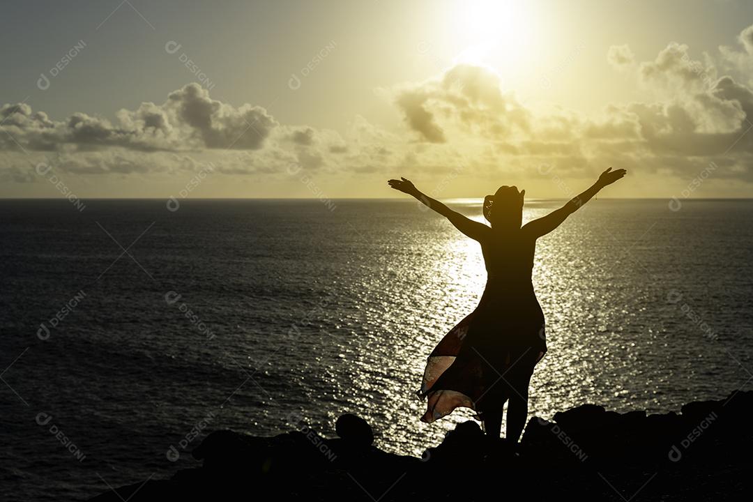 Foto Mulher no Penhasco Perfil Assistindo o Pôr do Sol Vestido Vermelho Transparente