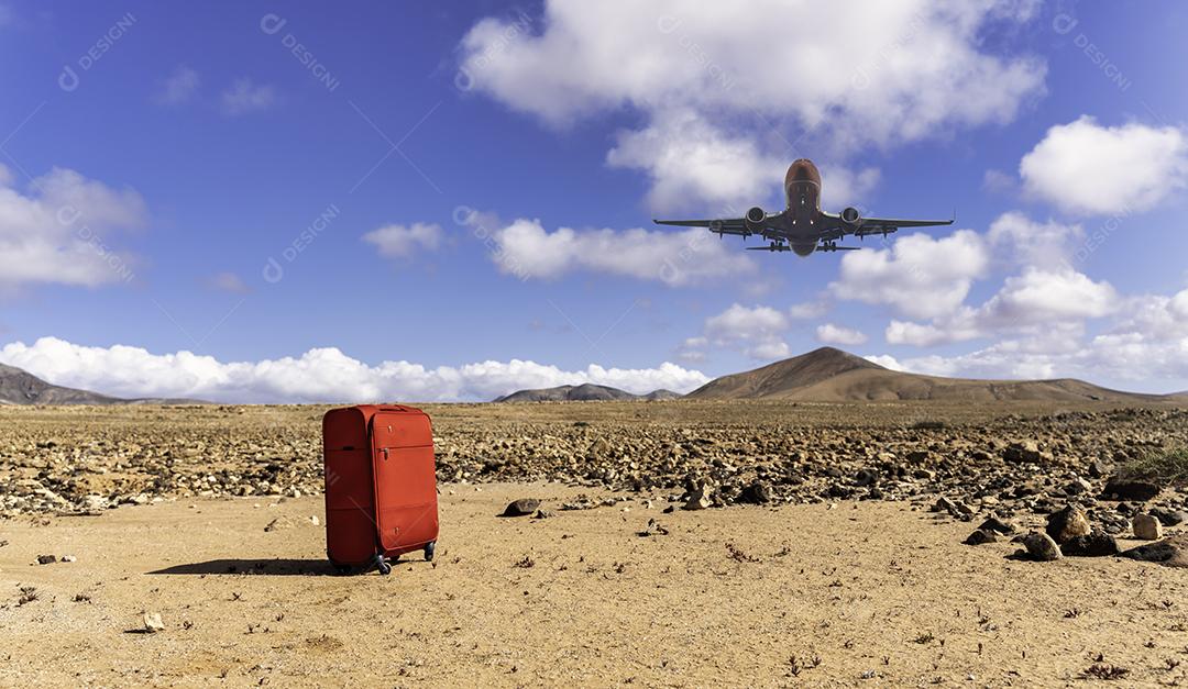 Foto Mala Vermelha Em Primeiro Plano Com Avião Pousando Sobre Paisagem Desértica
