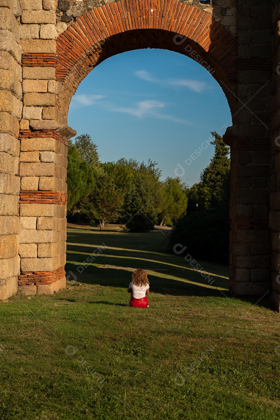 Mulher Sentada Na Grama Sobre Um Arco Do Aqueduto Imagem JPG