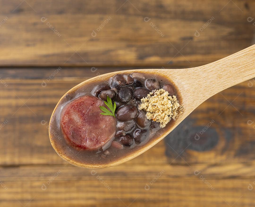 Feijoada Brasileira Tradicional em uma Colher Sobre Madeira Imagem JPG