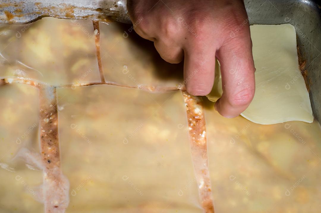 lasanha sendo montada à mão colocando queijo Imagem JPG