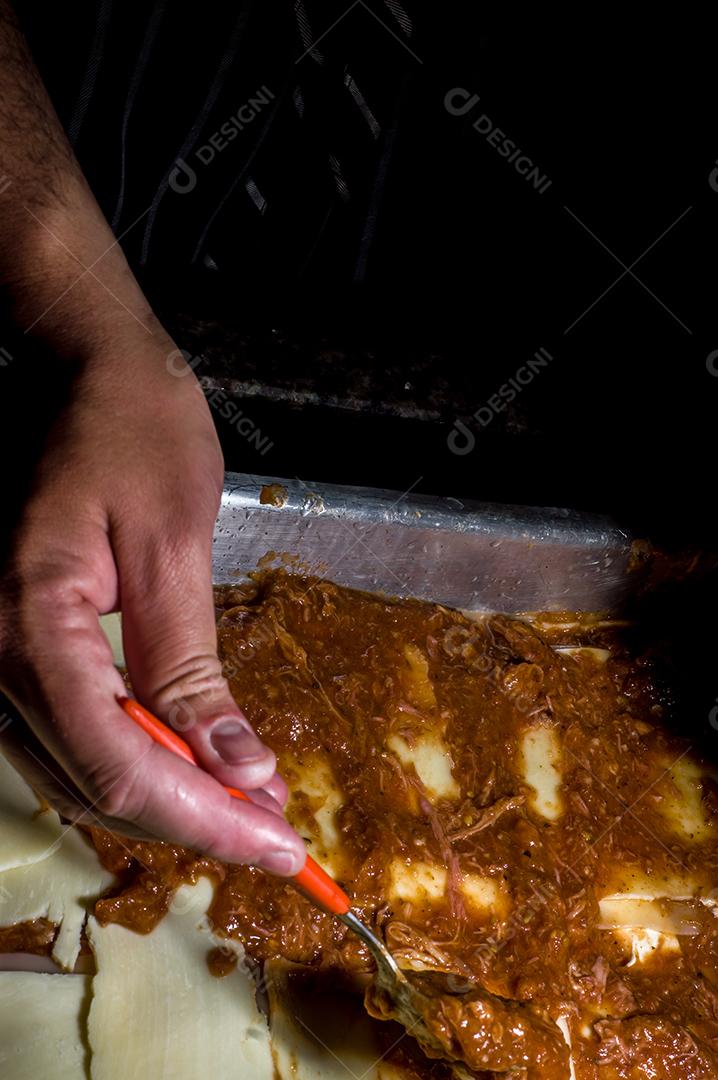 lasanha sendo montada à mão colocando queijo Imagem JPG