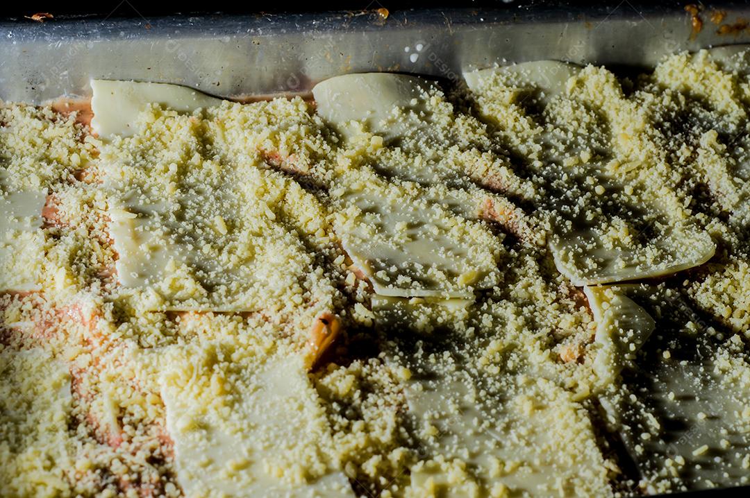 lasanha sendo montada à mão colocando queijo Imagem JPG