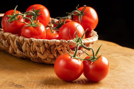 Tomates Em Uma Cesta De Palha Sobre Madeira Imagem JPG