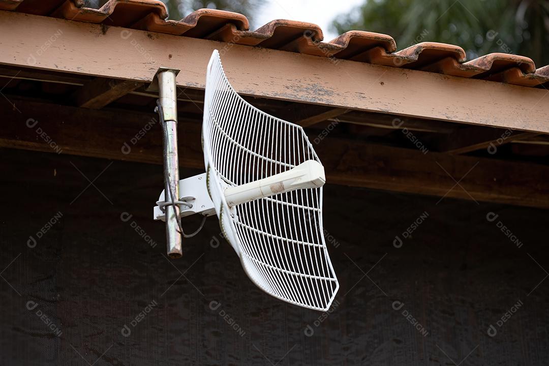 Antena branca apoiada no telhado de uma fazenda