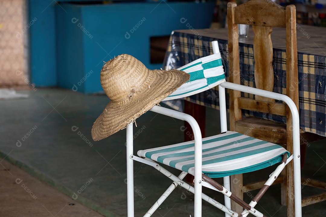 Cadeira de praia dobrável com chapéu de palha descansando em uma fazenda no interior