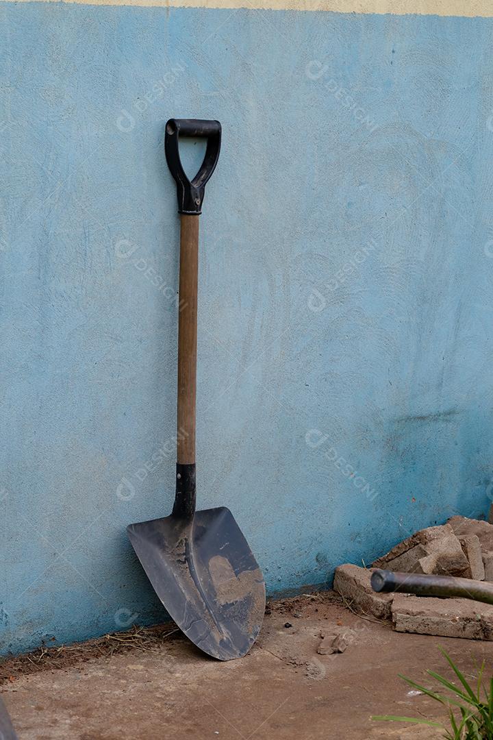 Pá metálica suja pequena com punho de madeira em um canteiro de obras