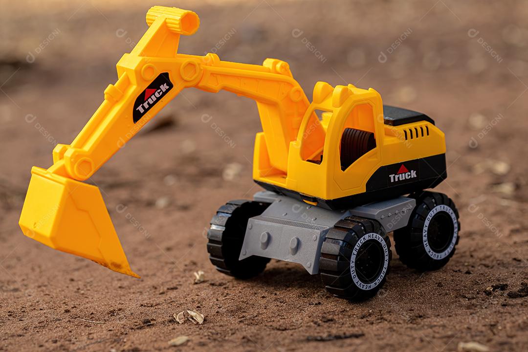 Miniatura de escavadeira de brinquedo de cor amarela e preta no chão