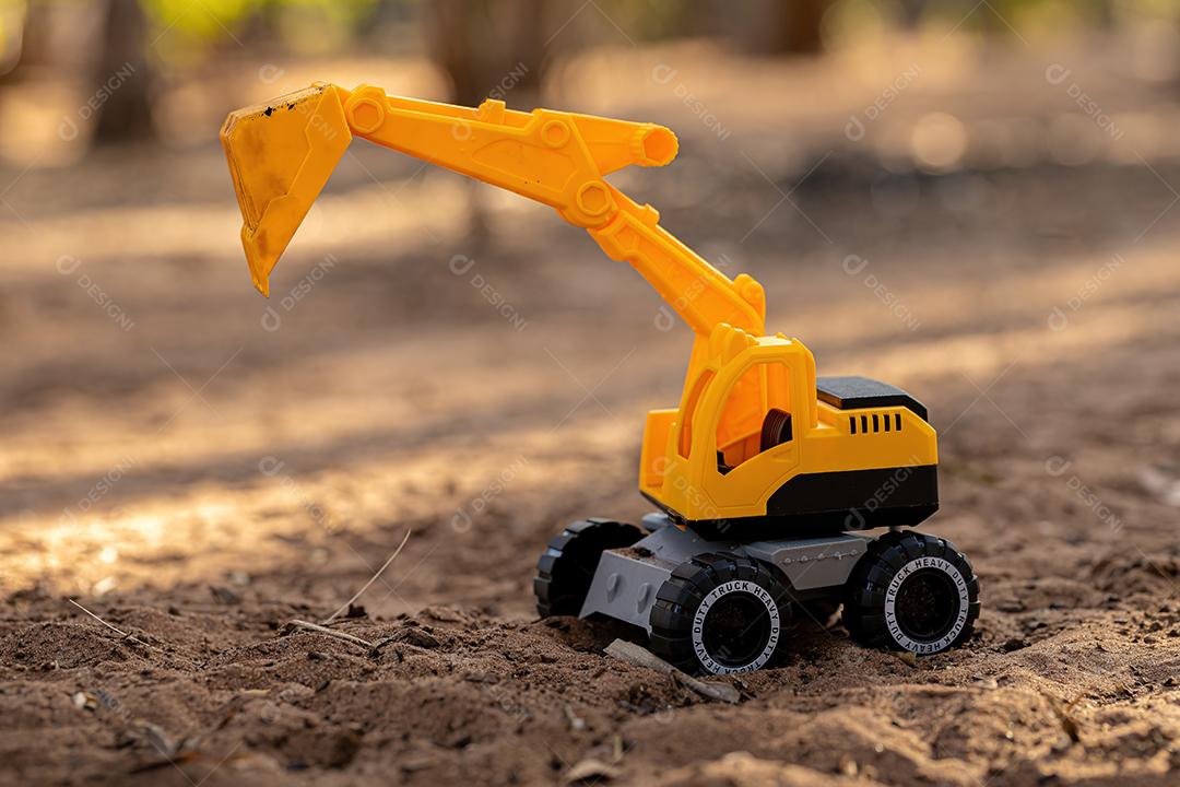 Miniatura de escavadeira de brinquedo de cor amarela e preta no chão
