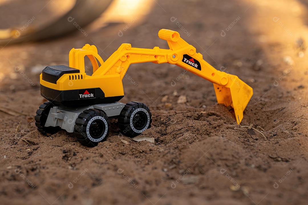 Miniatura de escavadeira de brinquedo de cor amarela e preta no chão