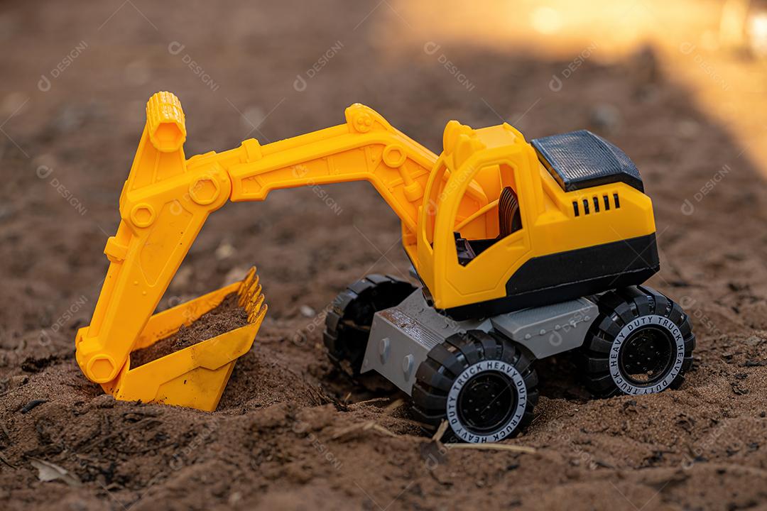 Miniatura de escavadeira de brinquedo de cor amarela e preta no chão