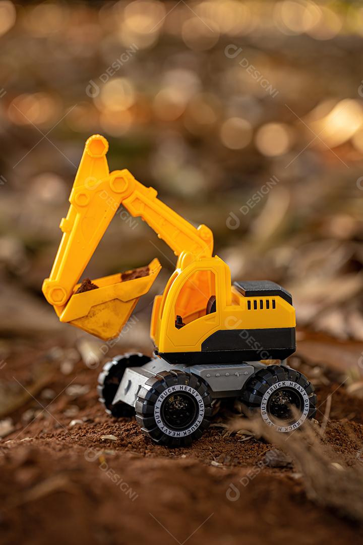 Miniatura de escavadeira de brinquedo de cor amarela e preta no chão