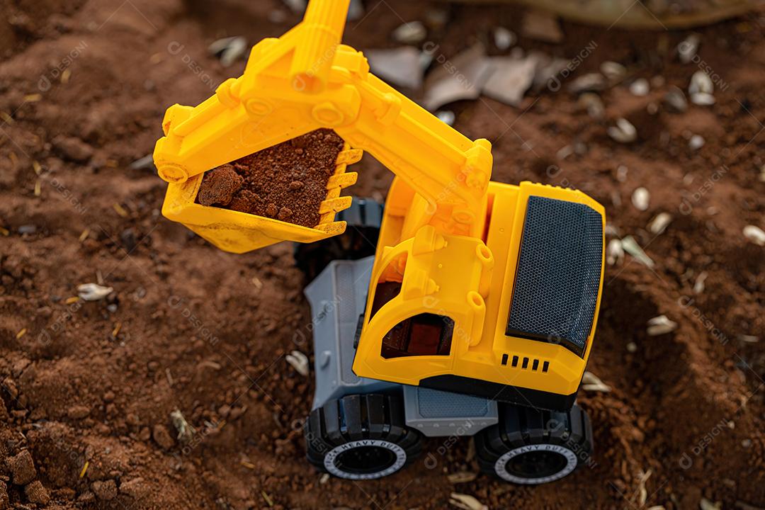Miniatura de escavadeira de brinquedo de cor amarela e preta no chão