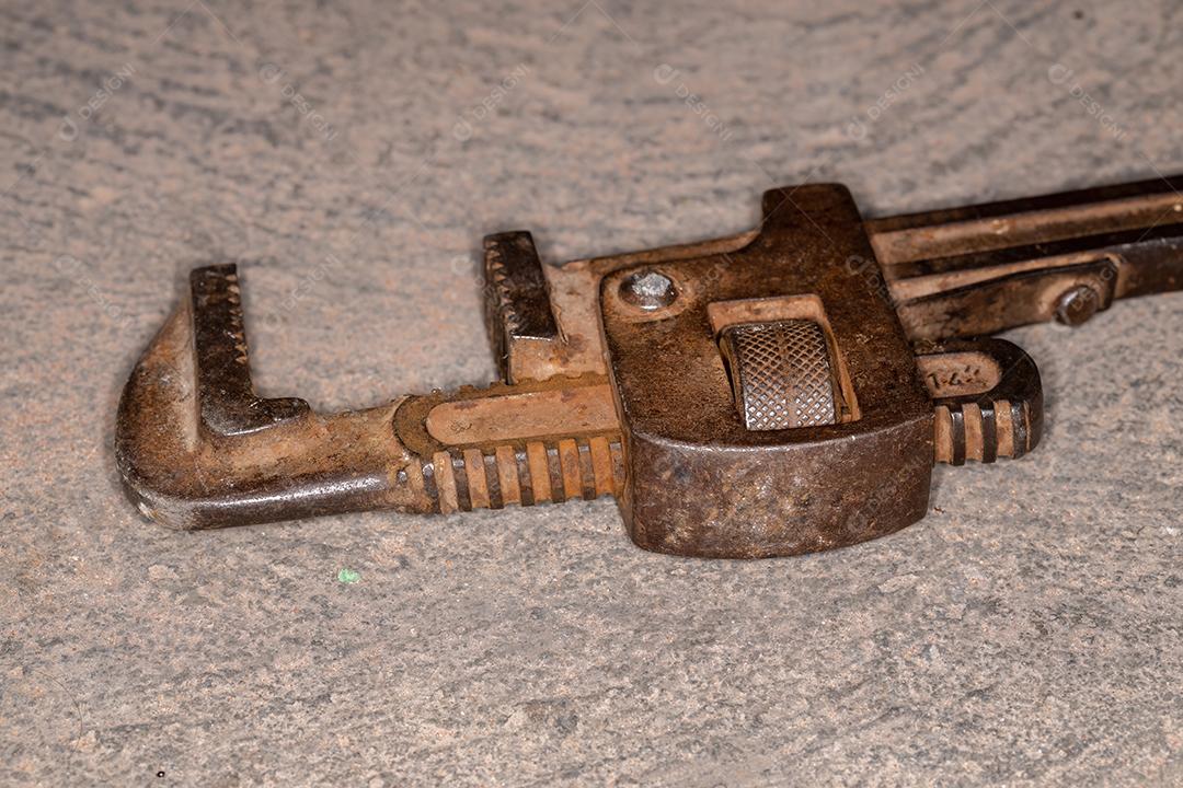 Ferramenta velha de chave de cano de metal enferrujado no chão de concreto