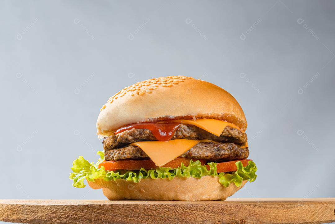 Hambúrguer com queijo tomate alface sobre mesa de madeira