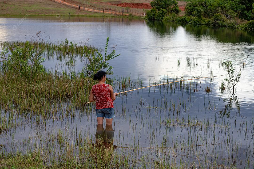 mulher pescando em um lago com as pernas na água